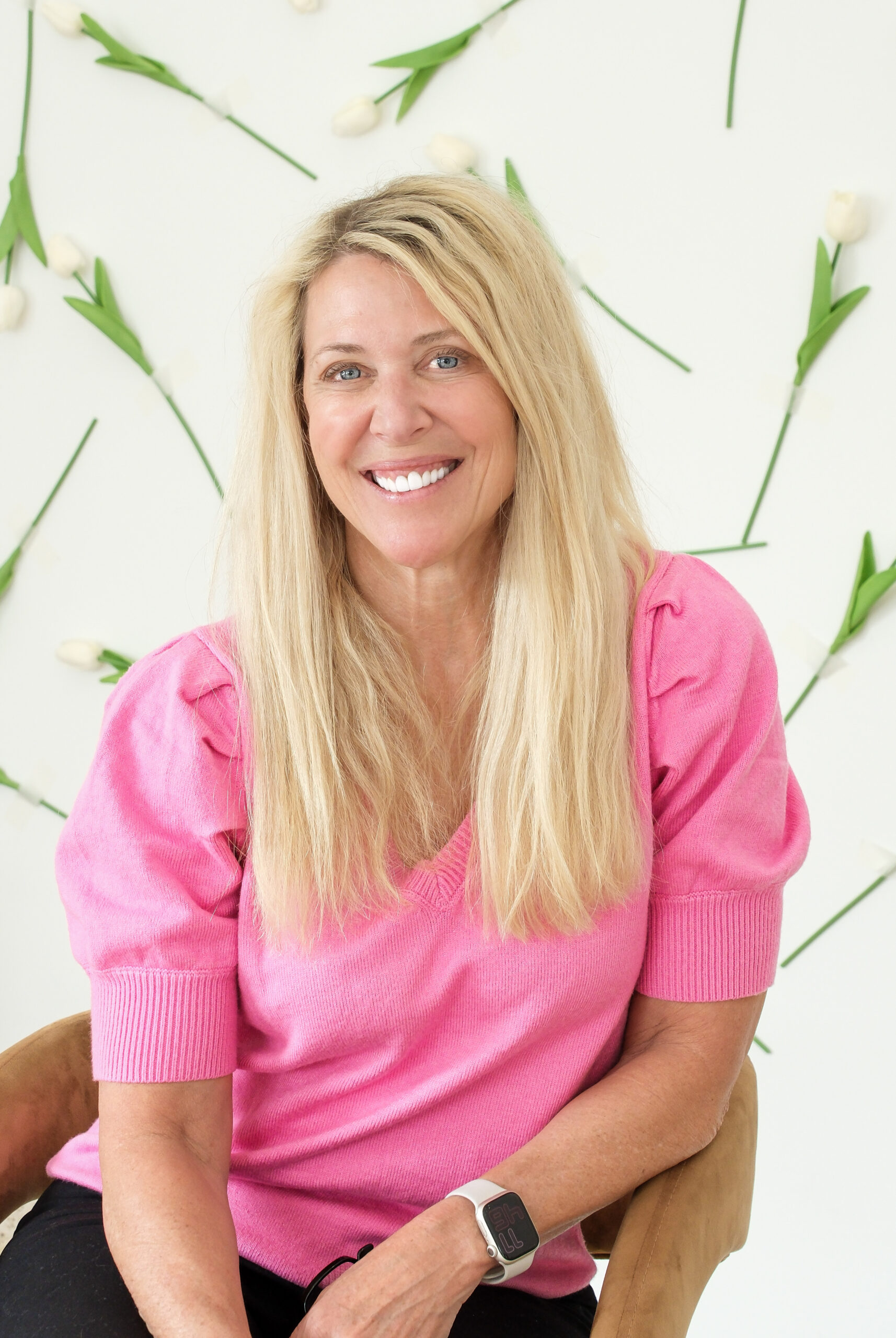 business woman in pink sweater sitting in front of a flower wall and  posing for professional branding photoshoot in Columbus, Oh